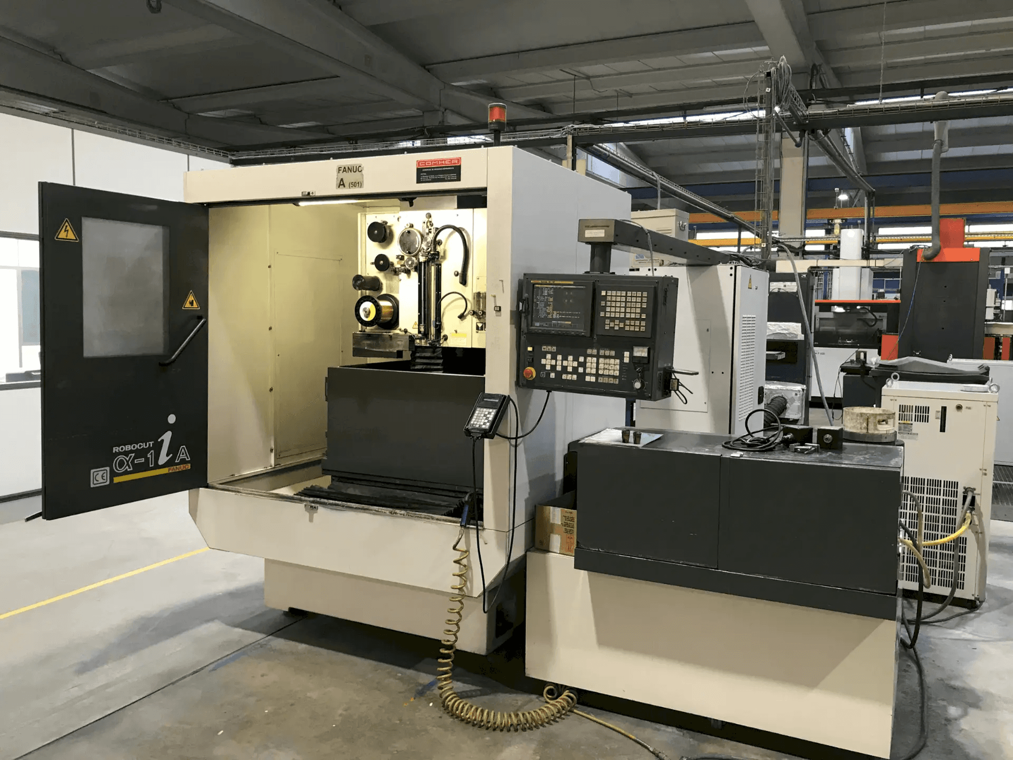 Centro di lavorazione verticale Mazak con sportello aperto che mostra gli utensili e i comandi, vista laterale, per applicazioni di lavorazione di precisione.